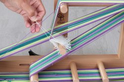 の下にリーシュを2番目の糸通して、リーシュの左側に1本の糸が残るまで通します。リーシュを上に通して次の縦糸（1番目の糸）の上に通します。